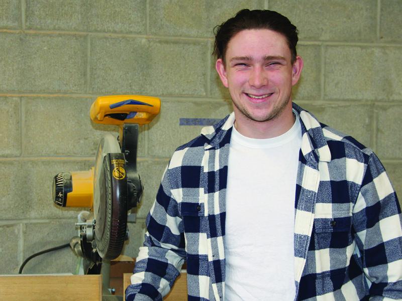 Thad Grierson stands in front of a saw in a building trades lab.