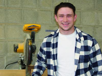 Thad Grierson stands in front of a saw in a building trades lab.