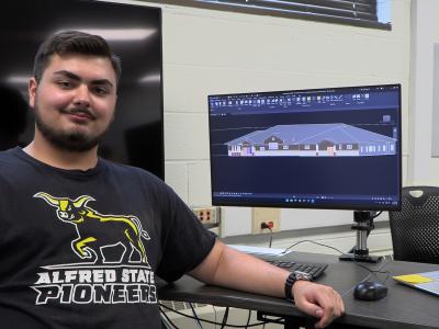 student poses in a lab with a computer screen displays a drawing