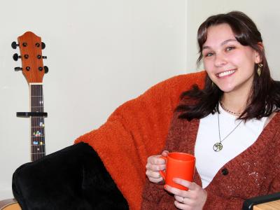 students sits in her dorm room with a warm drink