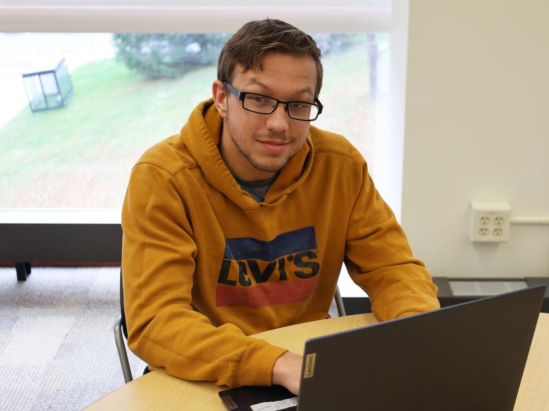Student sits behind laptop