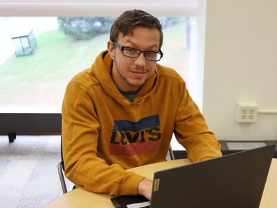 Student sits behind laptop