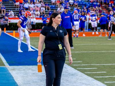 Alfred State alum Kelsey Curry walks the sideline prior to the start of a McNeese State football game at Florida.