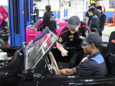 Instructor with student working on a car