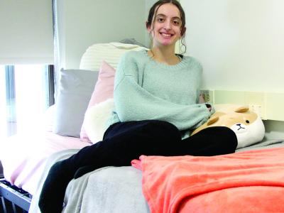 Gabriela Leite sits on her bed in her dorm room