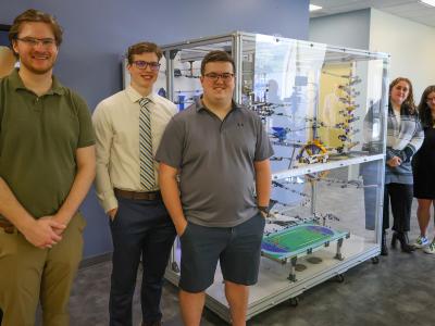 students stand with the marble run machine