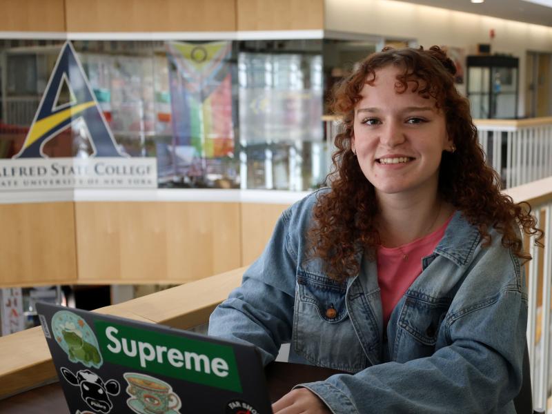 student smiling while she works on computer