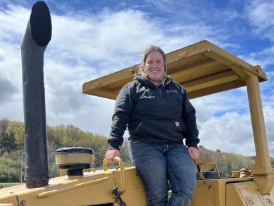 Student stands with heavy equipment machinery