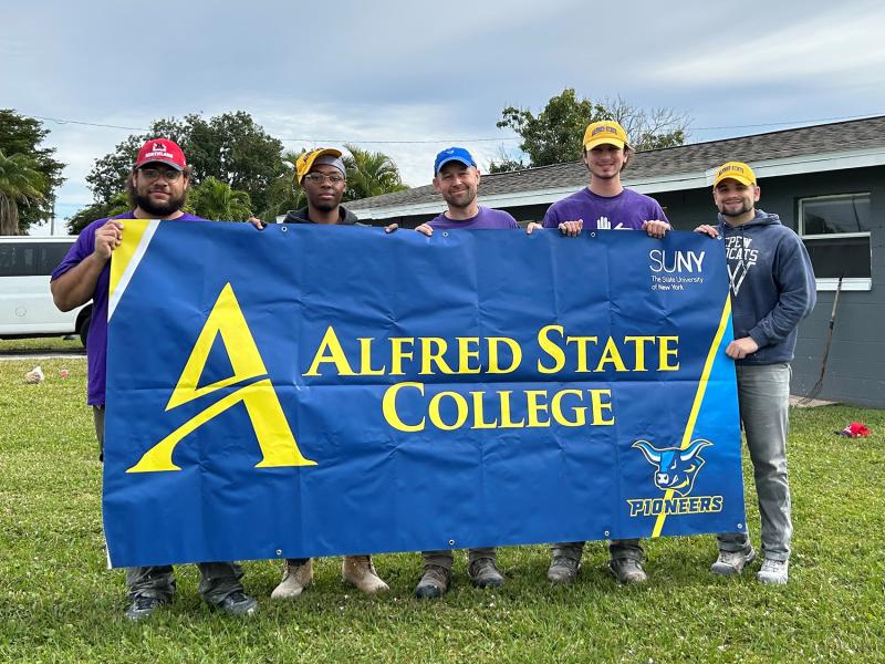 A group of Alfred State students hold a college sign