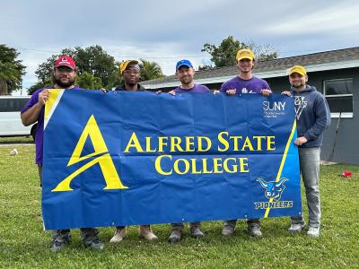 A group of Alfred State students hold a college sign