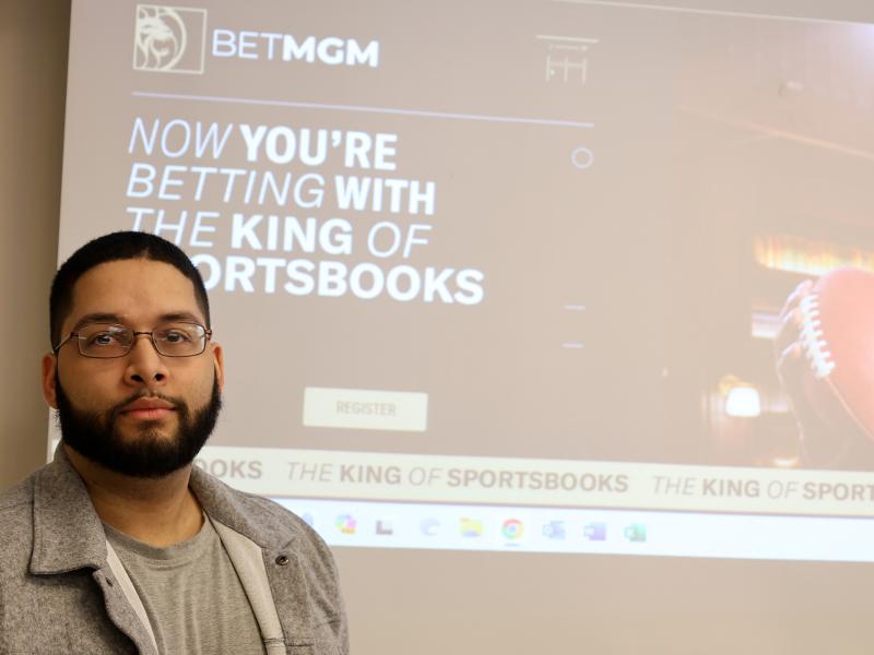 alumni stands in front of company advertisement