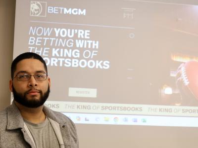 alumni stands in front of company advertisement