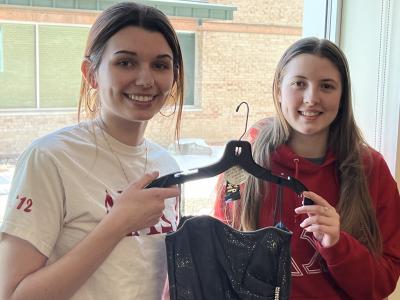 Pair of Delta Chi Omega sisters hold up a dress