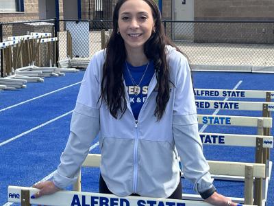 Student standing in between hurdles on the track.