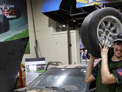 Quinn Scanlon holds a tire in front of a car.