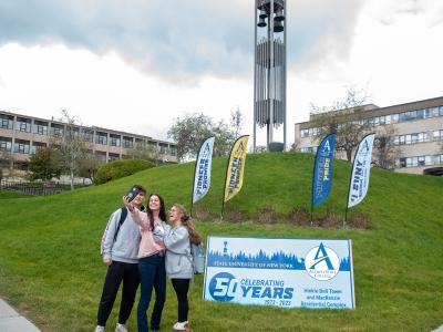 students pose in front of a bell tower