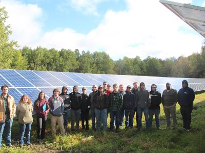 Tyler Uebelhoer stands with a class of Electrical Construction and Maintenance Electrician students at Alfred Community Solar after showing the class the set-up of the new Buffalo Solar project.
