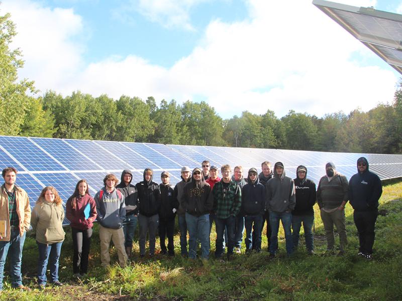 Tyler Uebelhoer stands with a class of Electrical Construction and Maintenance Electrician students at Alfred Community Solar after showing the class the set-up of the new Buffalo Solar project.