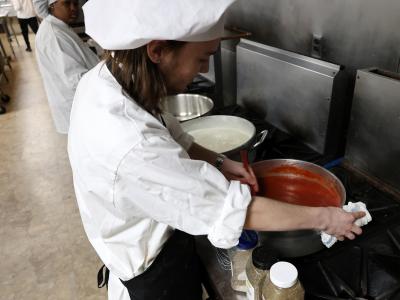 student stirs spaghetti sauce