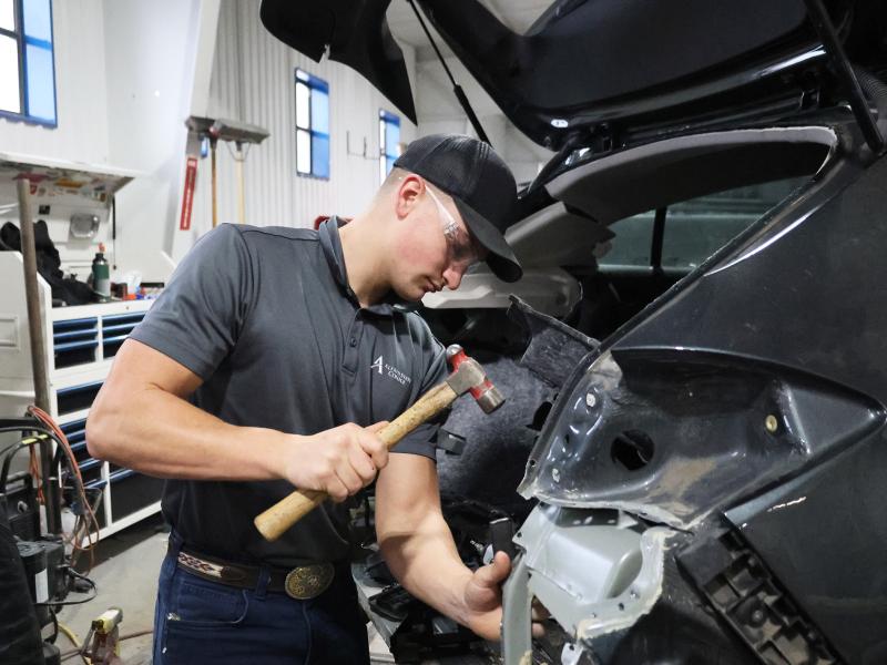 Student works on a wrecked car