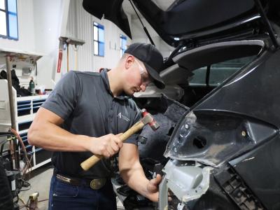 Student works on a wrecked car