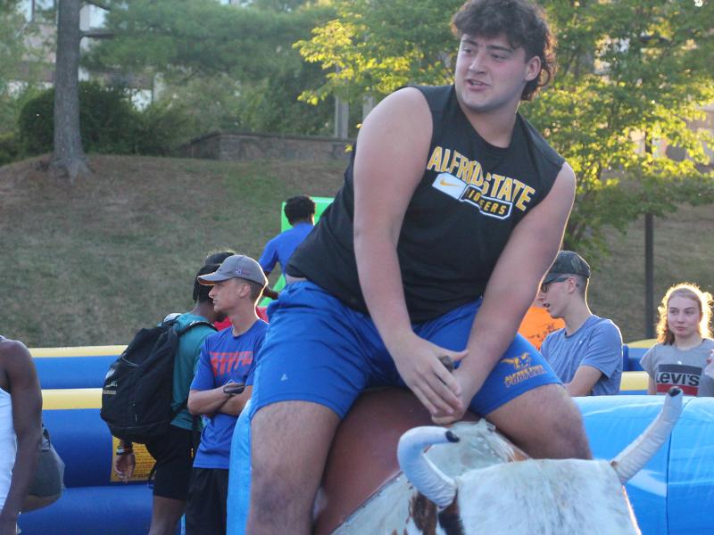 An Alfred State student rides a mechanical bull during the annual Week of Welcome carnival