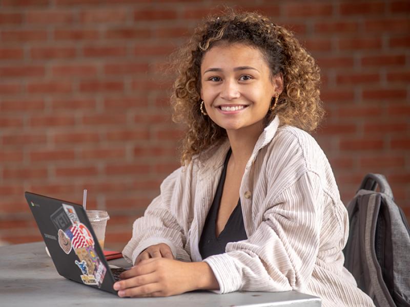 An Alfred State student works on her laptop outside.
