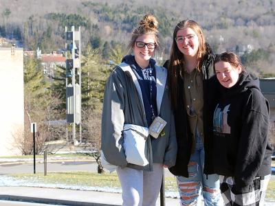 Alfred State students pose for a picture with the bell tower in the background.