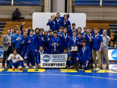 Alfred State wrestling team poses with championship banner and trophy