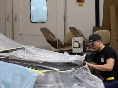 student works on the body of a car