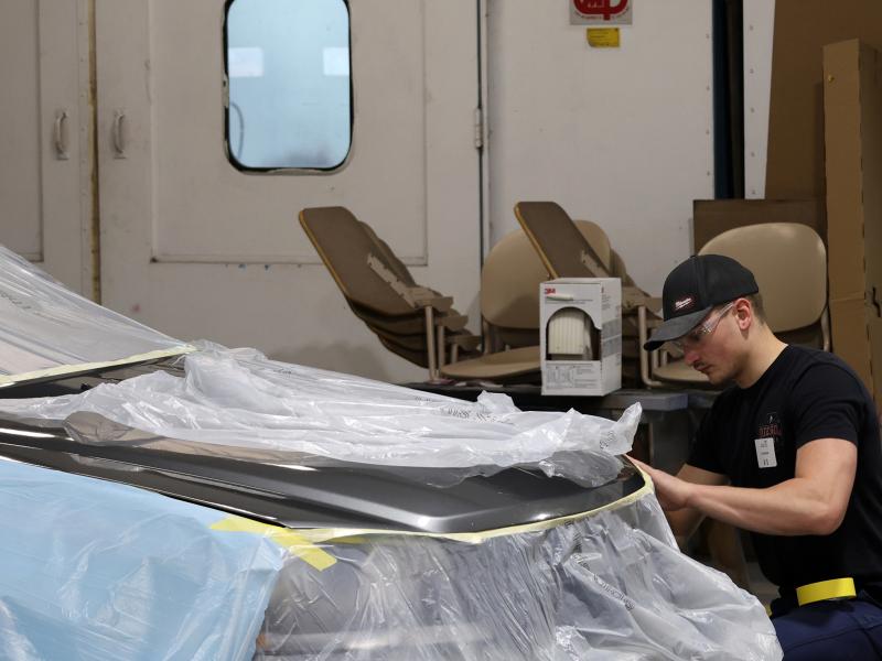 student works on the body of a car