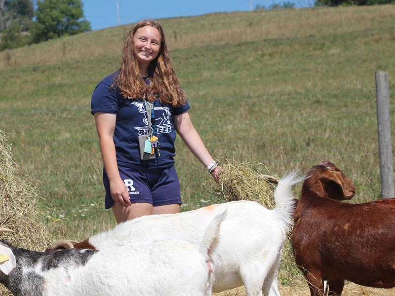 smiling student with the goats on the ASC farm
