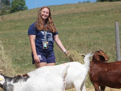 smiling student with the goats on the ASC farm