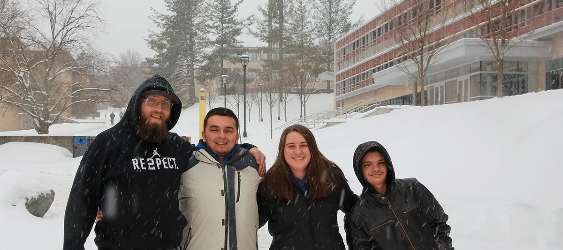 Four students outside on campus in the snow.