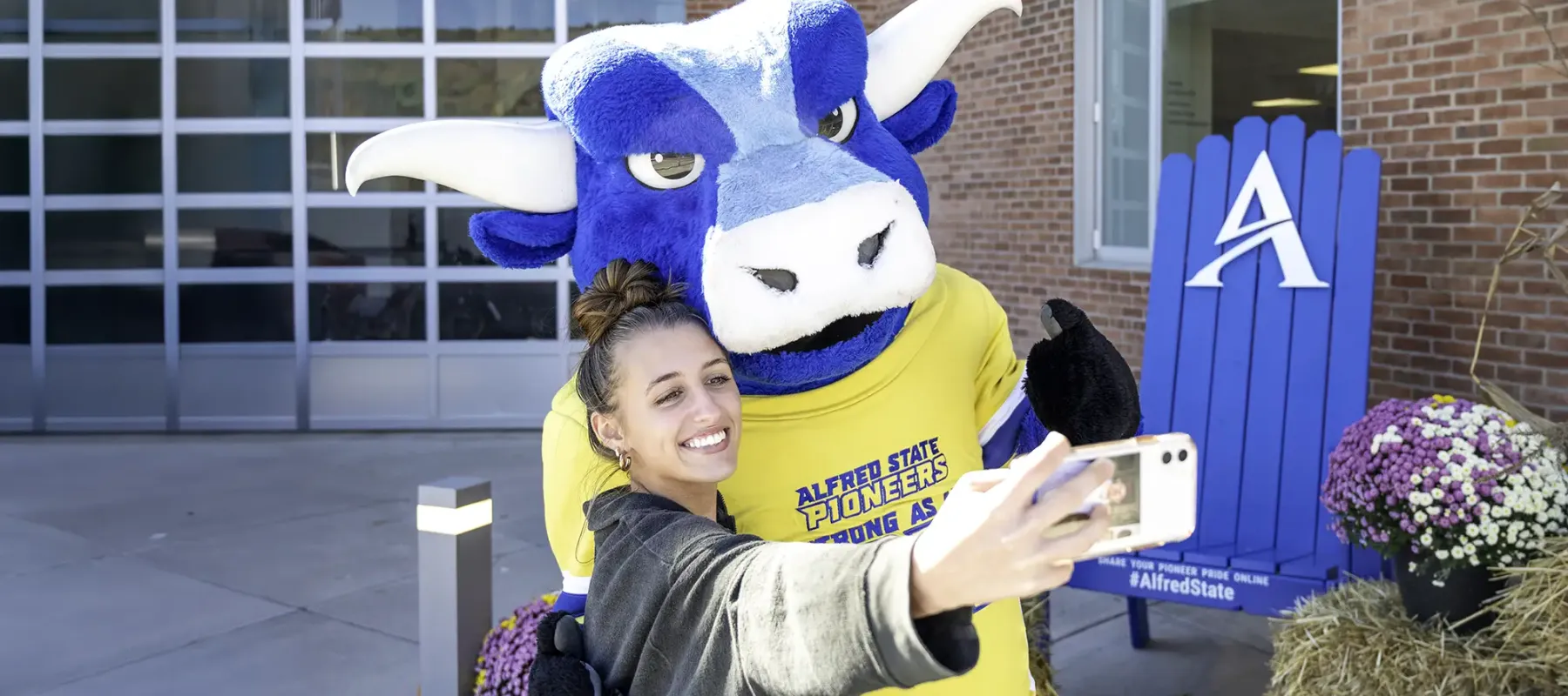 Alfred State's mascot taking a selfie with a student