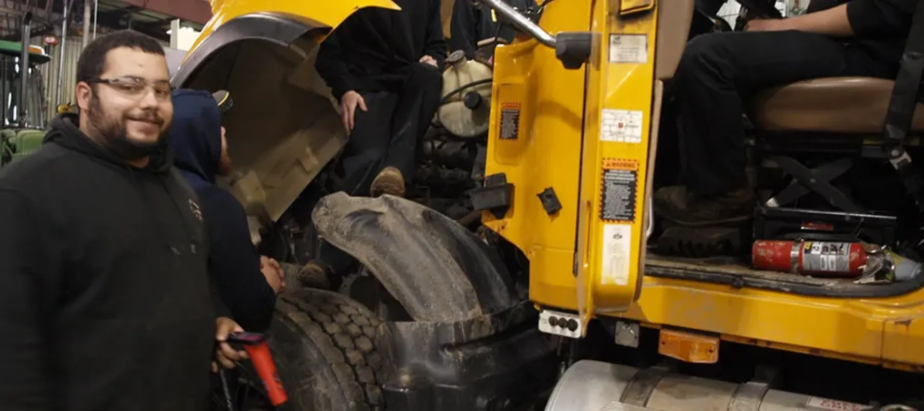 Students work on truck engine.