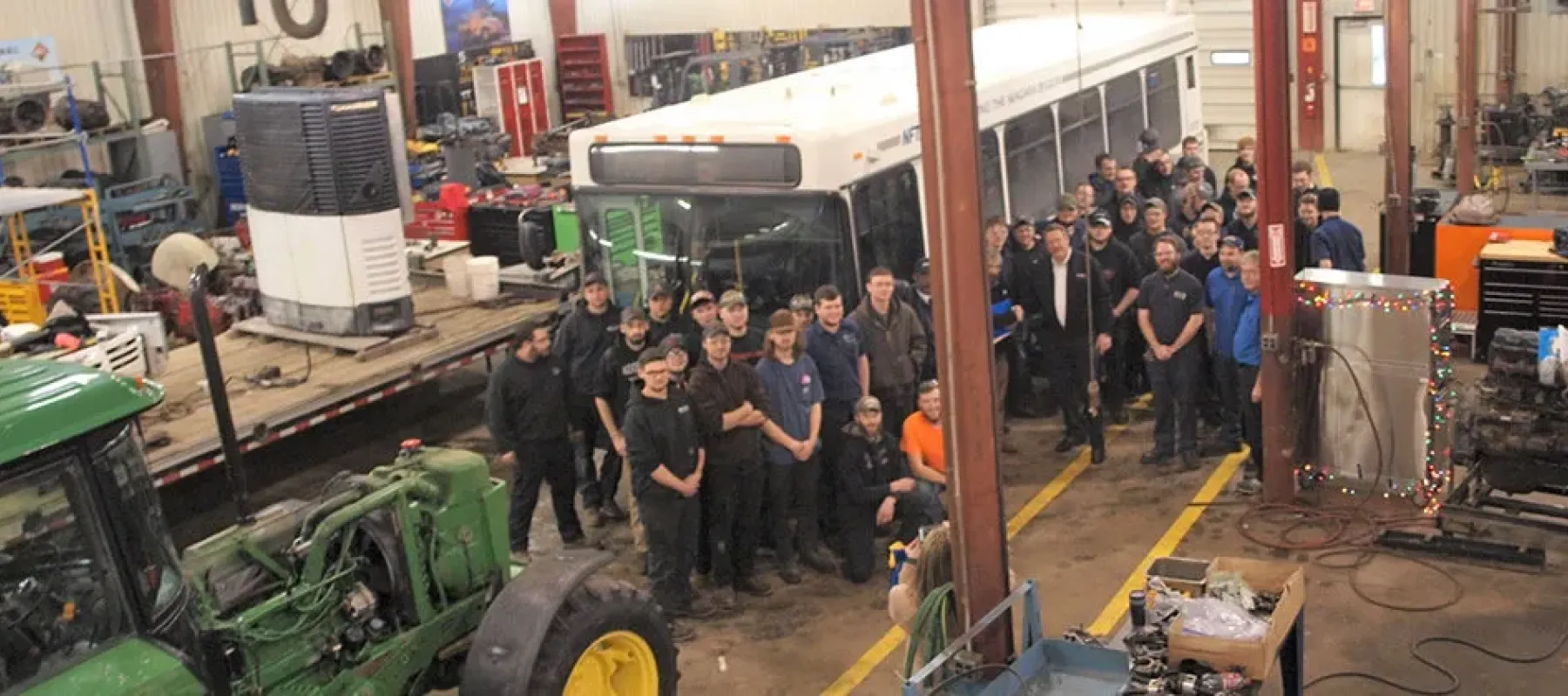 Heavy Equipment, Truck & Diesel Technician pose for picture inside shop on Wellsville campus.