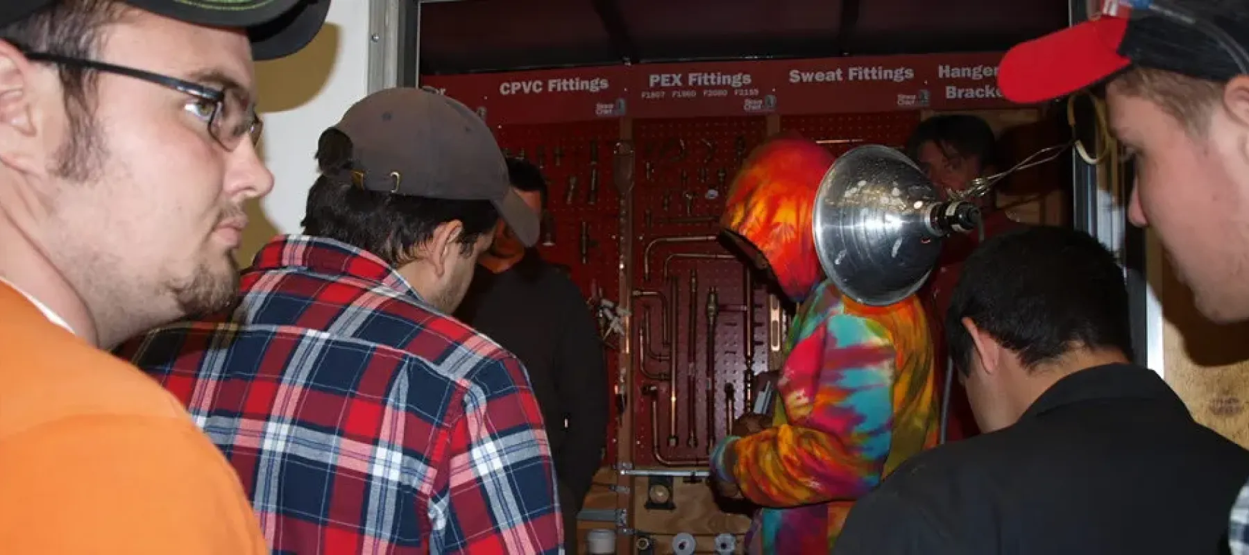 Students gathered around display with CPVC, PEX, and Sweat fitting examples.