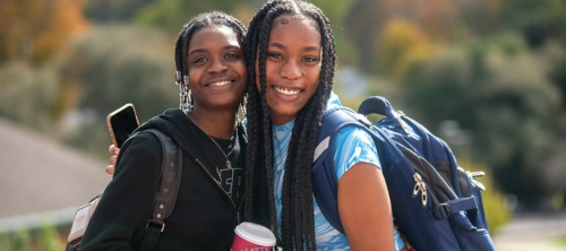 Two students posing for picture outside.