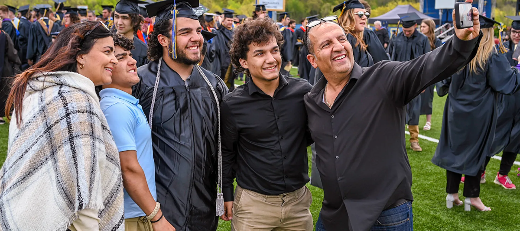 Student taking photo with family at graduation.