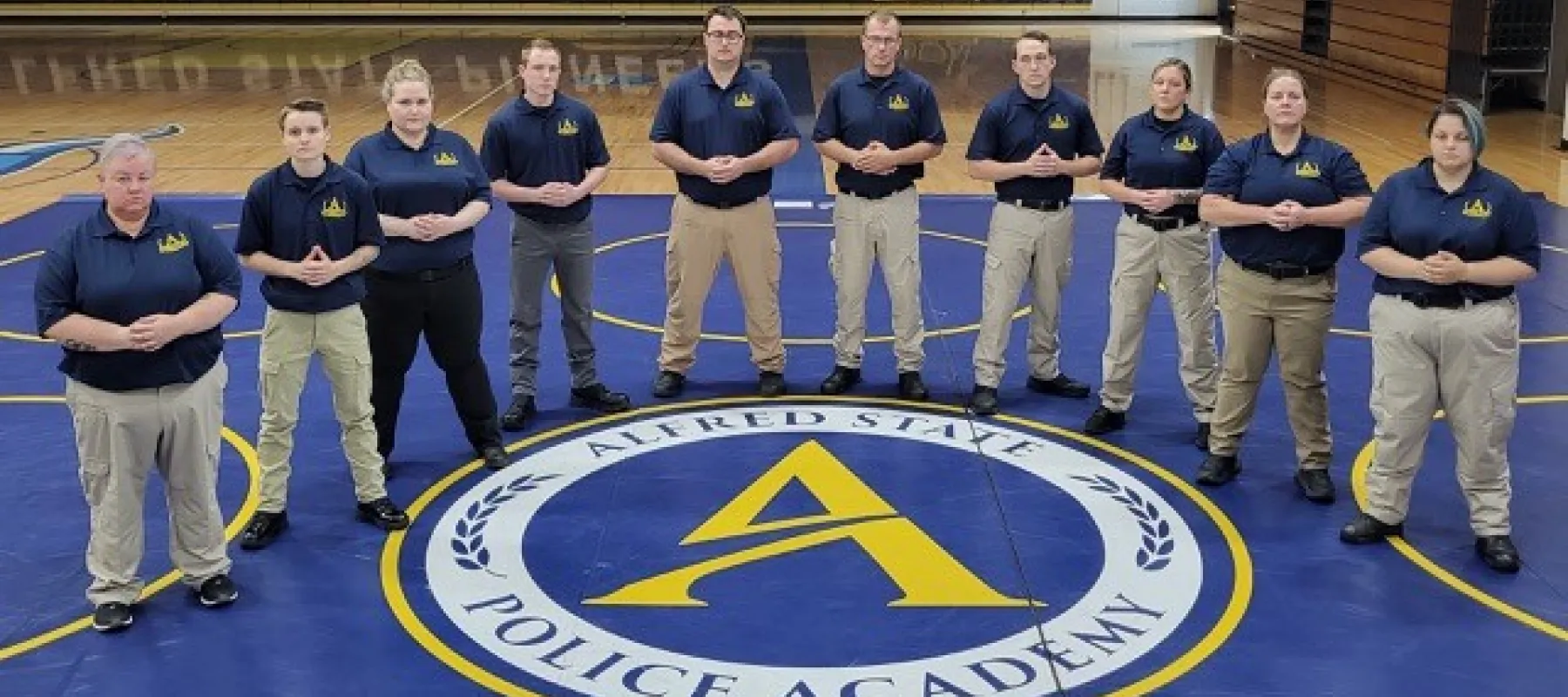 Instructors in Alfred State police academy standing inside gym used for training.