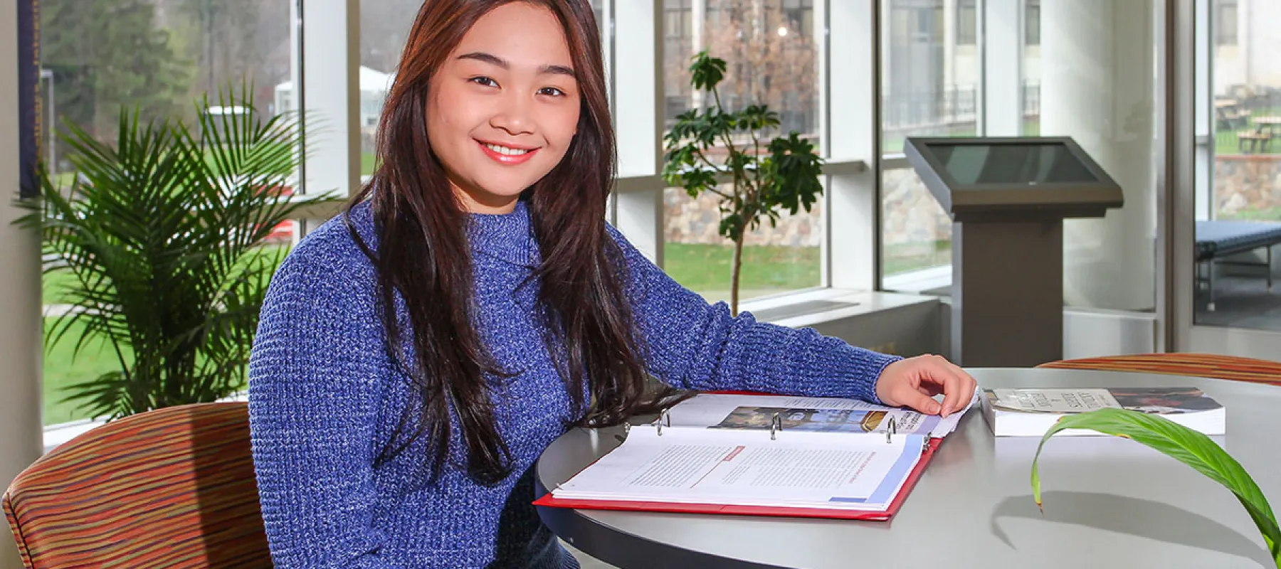 Student sitting at table with binder in Student Leadership Center.