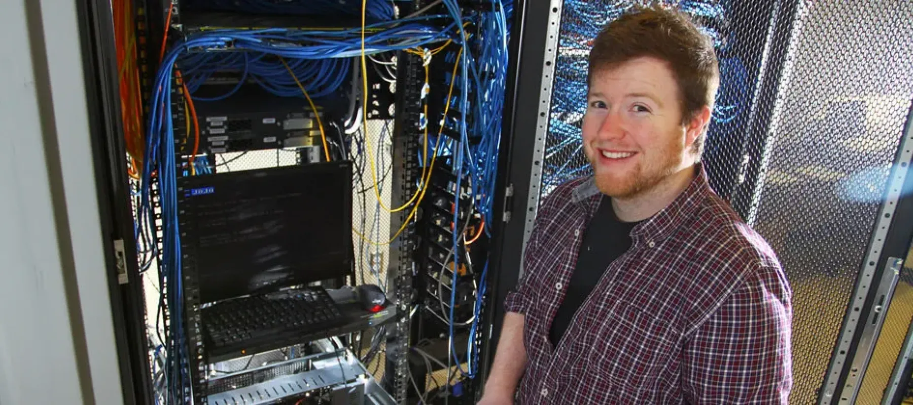 IT student posing next to network rack.