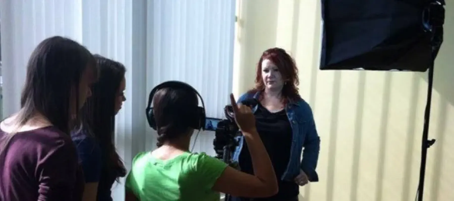 Woman poses for three students with a camera.