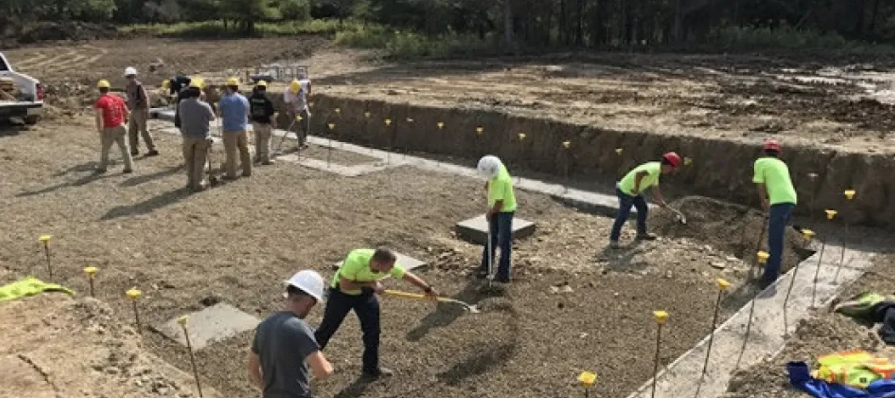 People working on construction site to spread gravel with shovels.