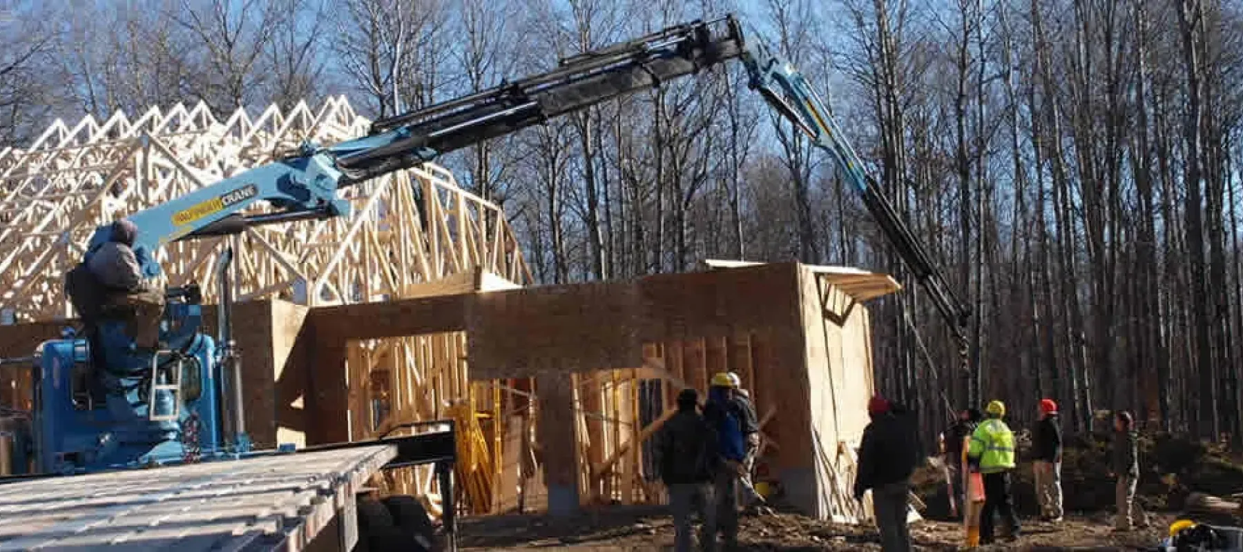 People use crane to position trusses on new building construction.