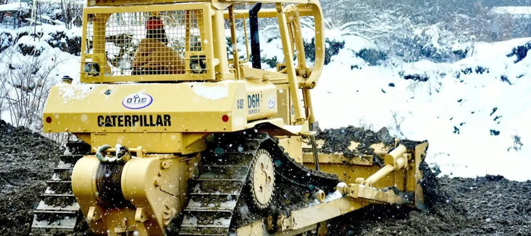 Person operating Caterpillar bulldozer outside in the winter.