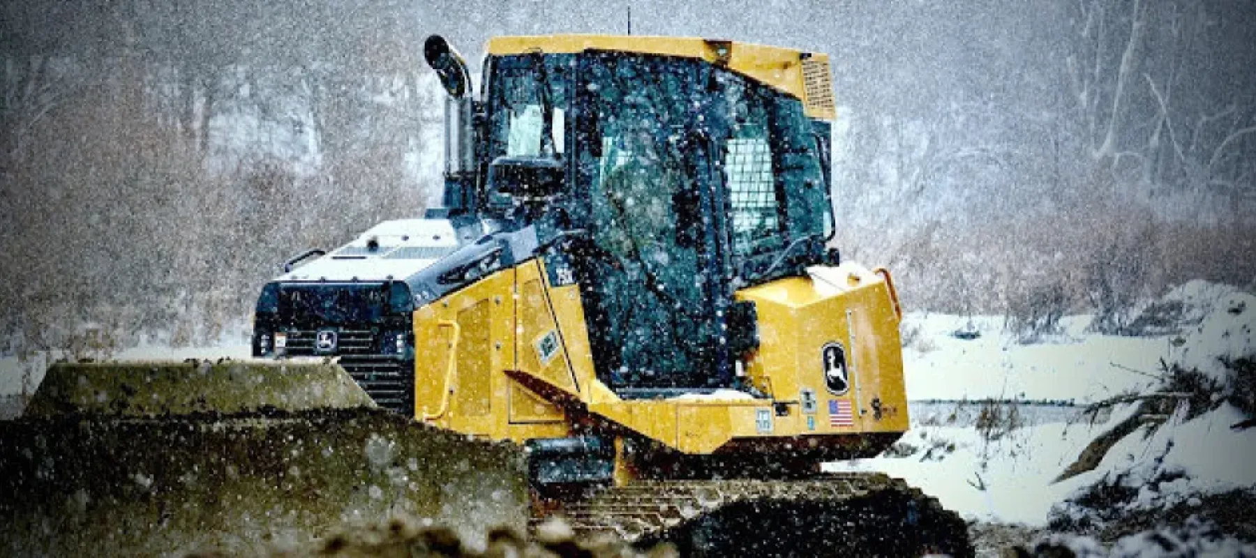 Heavy machinery sitting outside while it's snowing.