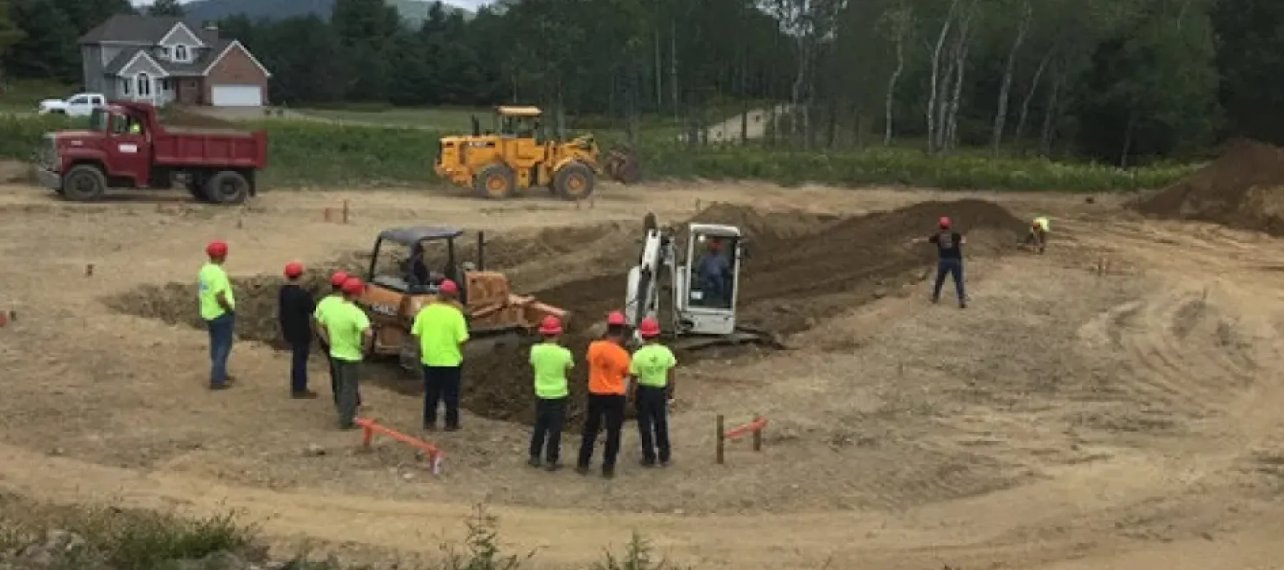 People outside with heavy machinery digging hole in ground.