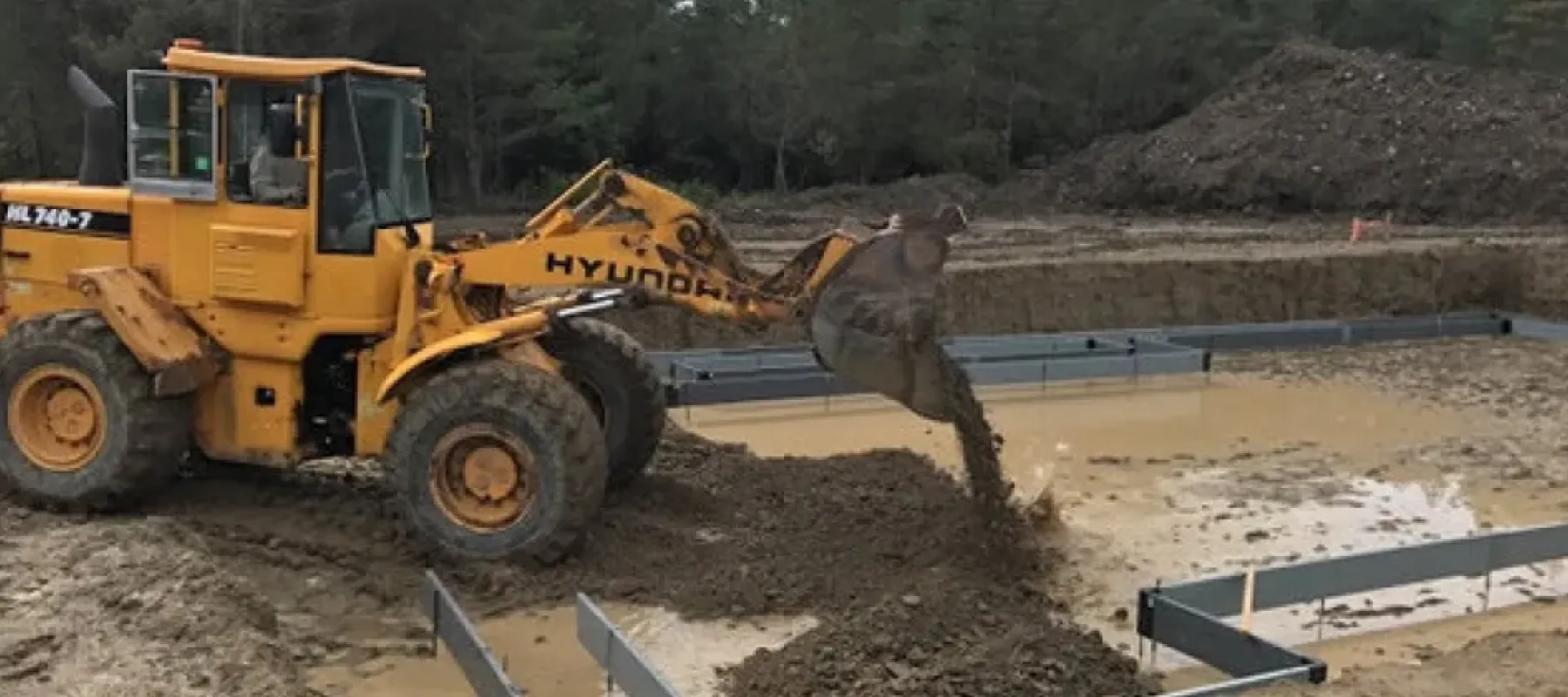 Person driving heavy equipment fill area with dirt.